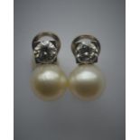 A pair of diamond and pearl earrings, each pearl mounted with a brilliant cut single stone diamond