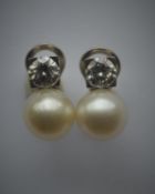 A pair of diamond and pearl earrings, each pearl mounted with a brilliant cut single stone diamond