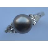 A black pearl and diamond three stone ring with large triangular shaped shoulders in 18 carat