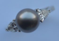 A black pearl and diamond three stone ring with large triangular shaped shoulders in 18 carat