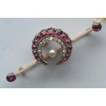 An unusual ruby and diamond crescent brooch, mounted on knife edge spacer with central pearl.