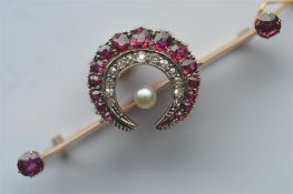 An unusual ruby and diamond crescent brooch, mounted on knife edge spacer with central pearl.