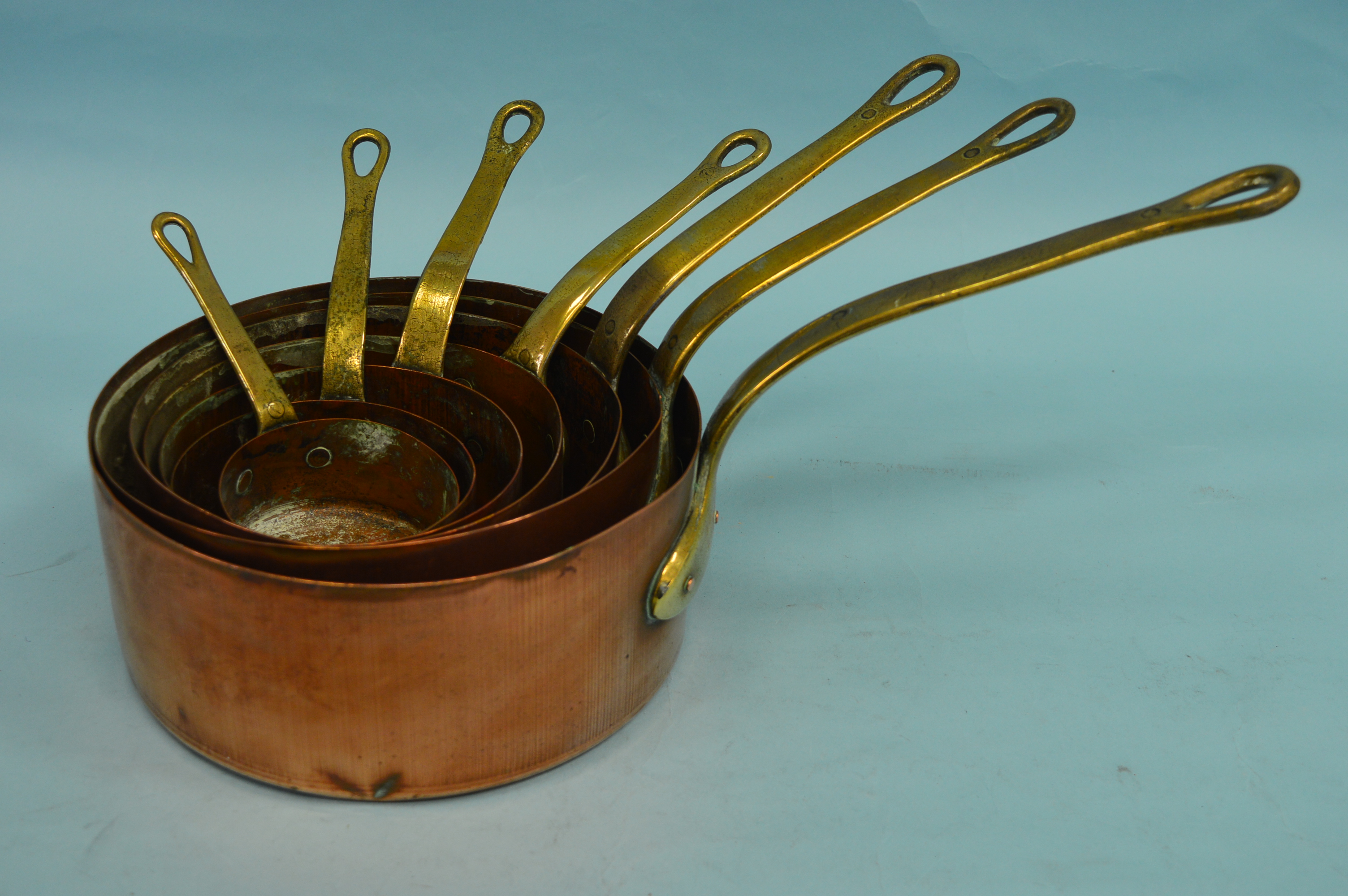 A set of six set copper and brass saucepans. Est.