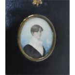An oval portrait of a lady in brass mounted frame.