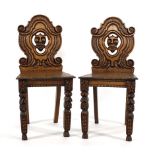 A pair of Victorian oak hall chairs, the backs carved with grotesque masks Wear commensurate with