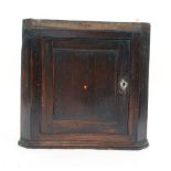 A George III oak hanging corner cupboard, the panelled door inlaid with a heart motif, w. 62 cm