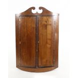 A George III mahogany and rosewood crossbanded hanging corner cupboard of bow fronted form, w. 64 cm