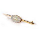 A yellow metal bar brooch set centrally with an oval opal, w. 5.4 cm, opal measures 1.6 x 0.9 cm