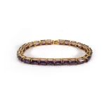 A 9ct yellow gold articulated bracelet set twenty four baguette cut purple coloured stones, presumed