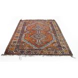 A Persian-style rug, the red ground decorated with a geometric design within a red and blue