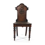 A 19th century mahogany hall chair, the shaped back with a floral armorial motif CONDITION REPORT: