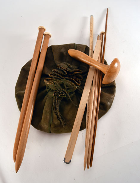 A Tunisian (?) crochet hook, three ivory mounted knitting needles, a green leather bag and various