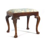 An 18th century and later walnut and upholstered stool on four moulded cabriole legs and pad feet