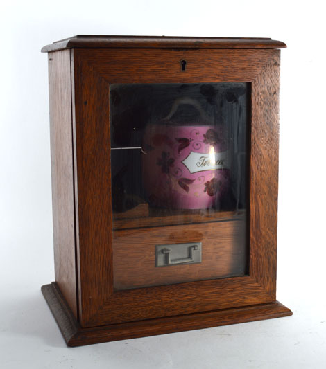 An Edwardian oak and glazed smokers cabinet, h. 28 cm, together with an associated tobacco jar