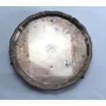 A miniature silver salver of circular form, the gadrooned border above three claw and ball feet,