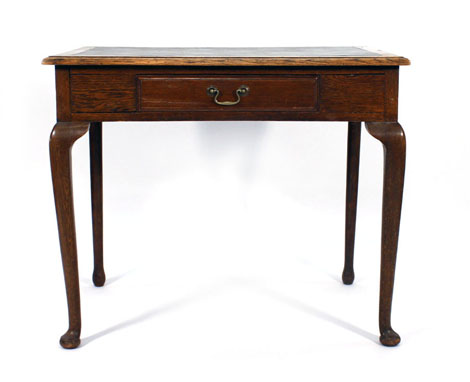 An early 20th century oak writing table, the frieze with a single drawer, on four cabriole legs with