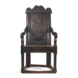 A 17th century and later oak Wainscot chair, the carved top rail over a panelled back with floral