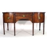 A George III mahogany bow fronted sideboard, the central drawer flanked by two doors on turned and
