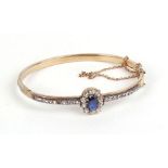 A yellow metal bracelet set centrally with an oval sapphire in a surround of ten old cut diamonds,