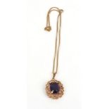 A yellow metal fine curblink necklace suspending a 9ct yellow gold scrollwork pendant set purple