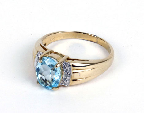 A 10ct yellow gold ring set centrally with a pale blue oval stone and small diamonds,