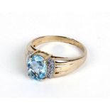 A 10ct yellow gold ring set centrally with a pale blue oval stone and small diamonds,