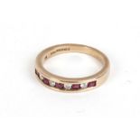 A 9ct yellow gold ring set five red coloured stones interspersed with four diamonds in a channel