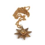 A yellow metal curblink necklace suspending a filigree work pendant of flowerhead form