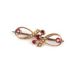 A yellow metal bar brooch of openwork design set seed pearls red coloured stones, w. 3.