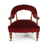 An early 19th century mahogany and button upholstered fireside armchair on turned legs with