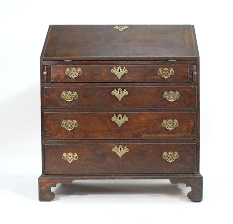 A George III and later oak bureau, the fall front enclosing a fitted interior over four graduated