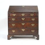 A George III and later oak bureau, the fall front enclosing a fitted interior over four graduated