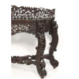 An Anglo-Indian hardwood bow fronted side table with an intricately carved frieze on four matching