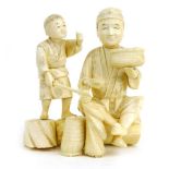 A Meiji carved ivory figural group modelled as a father and son consuming their catch, h.