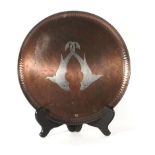 An Arts & Crafts beaten copper plate with silvered aquatic decoration, by Hugh Wallace, bearing