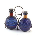 A pair of Harden Star blue moulded glass fire grenades in a fitted wire holder, h. 17 cm CONDITION