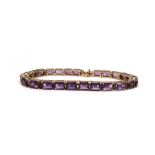 A 9ct yellow gold articulated bracelet set twenty four baguette cut purple coloured stones, presumed