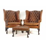 A pair of early 20th century leather and button upholstered wingback armchairs on mahogany claw feet