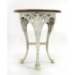 A late Victorian garden table, the mahogany circular top on a white cast iron base, the three legs