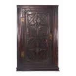 An 18th century and later panelled oak hanging corner cupboard with carved and moulded decoration,