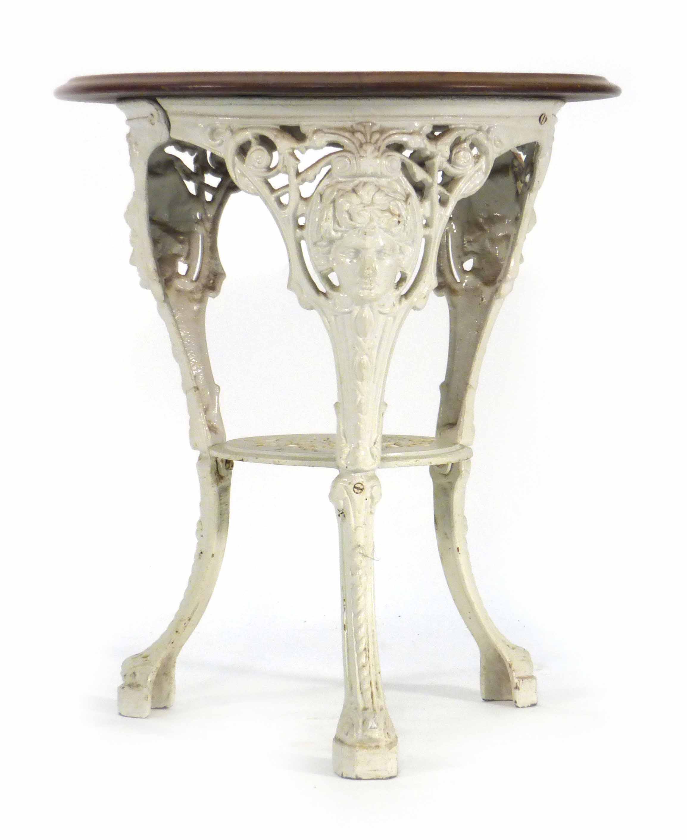 A late Victorian garden table, the mahogany circular top on a white cast iron base, the three legs