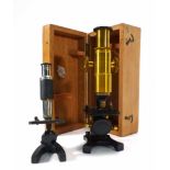 A 20th century brass and enameled students microscope together with another similar CONDITION