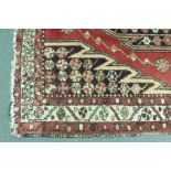 A Persian woollen rug, the central motif within a red ground and cream border, 150 x 105 cm,