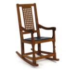 A Peter 'Rabbitman' Heap oak and leather seated rocking chair with lattice panelled back and