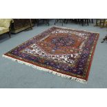 A modern Persian hand knotted woollen carpet, decorated with stylised motifs on a red ground
