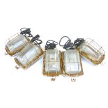 A set of four rectangular industrial steel wall lights with moulded glass shades and steel grills