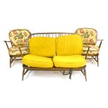 An Ercol stained beech two seater spindle back sofa together with two matching armchairs with