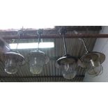 A set of four black enamelled ceiling lights on shafts with steel grills and moulded glass shades