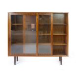 A 1960's rosewood bookcase with twin glazed sliding doors and six adjustable shelves on circular