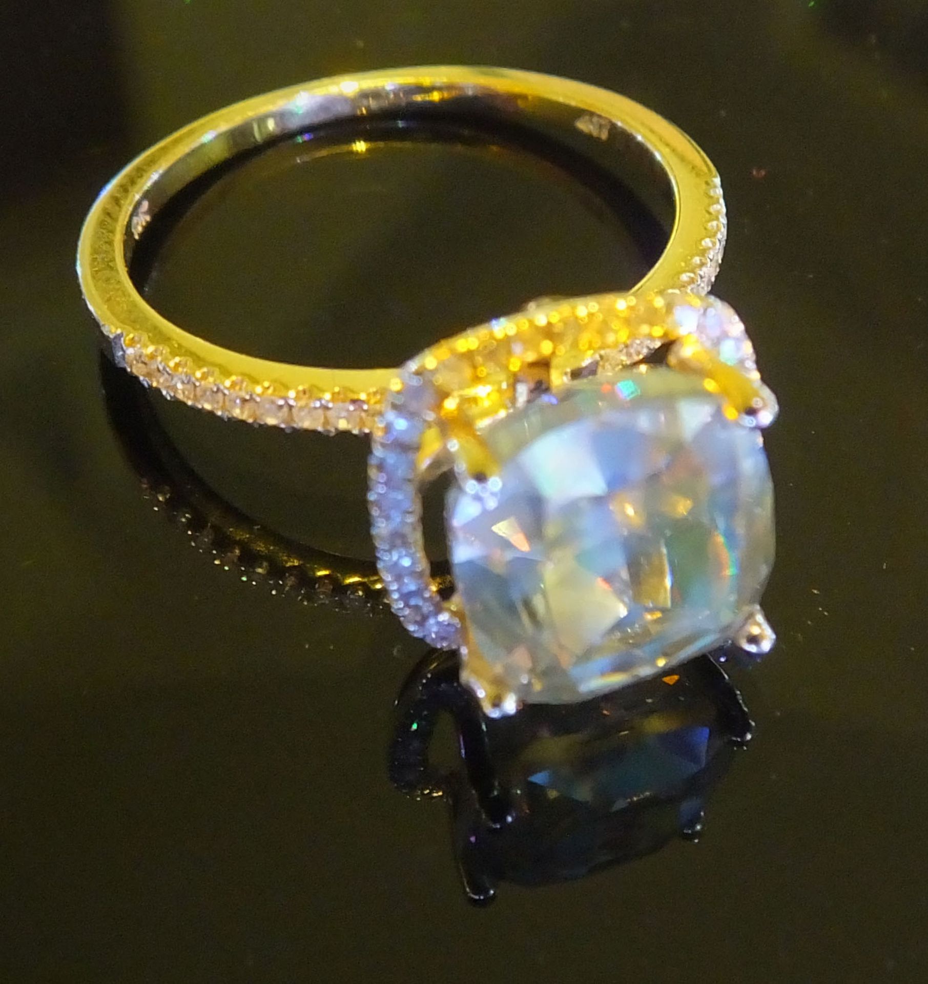 A 4.06 carat Cushion cut diamond, set in yellow gold Halo setting surrounded by diamonds.